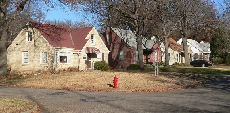 A two-story house with a dark shingle roof and a stone chimney in Lincoln